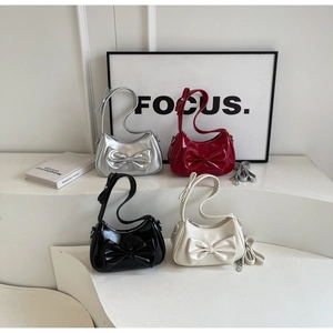 Close-up of four colorful bow underarm bags in silver, red, black, and beige leather