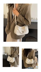 Detail of white half-moon shoulder bag with pearl butterfly chain and adjustable strap