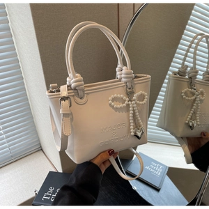 Gros plan du sac à main blanc avec lettres embossées et nœud en perles élégant