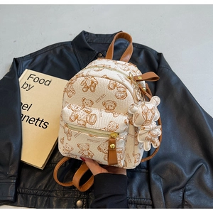 Détails d'un mini sac à dos avec motifs d'oursons, zips dorés et breloque peluche
