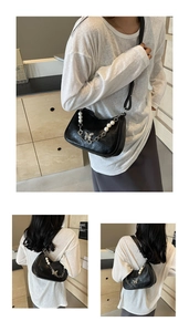 Detail of black hobo bag with metallic butterfly pendant and pearl decorative chain