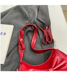 Detail of red glossy underarm bag featuring a large bow and adjustable shoulder strap