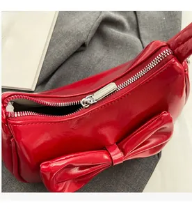 Close-up of smooth silver metal zipper on red glossy underarm bag with bow detail