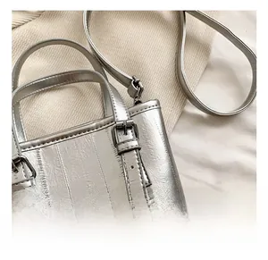 Detail of silver metallic bucket bag with pleated texture and polished metal buckle