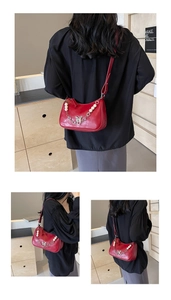 Detail of red glossy shoulder bag featuring metal butterfly pendant and pearl chain