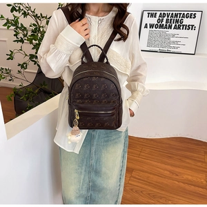 Detail of dark brown leather backpack featuring abstract patterns and a plush lamb pendant