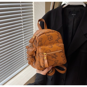 Gros plan d'un mini sac à dos marron avec imprimé ours en peluche et pendentif assorti