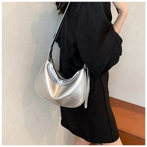 Modische silberne Hobo-Tasche aus Metall, getragen von einem Model zum schwarzen Kleid