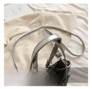 Detail of silver metallic bucket bag showing handle and detachable shoulder strap