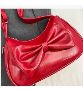 Close-up of bright red patent leather shoulder bag featuring a large decorative bow