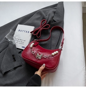 Close-up of wine red shoulder bag with pearl, flower and silver butterfly chain detail