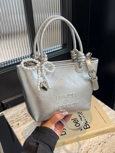 Sac seau métallisé argenté avec nœud en perles et pendentif cœur sur marbre