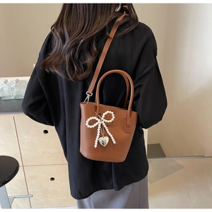 Brown lychee texture bucket bag with pearl bow and silver heart pendant detail