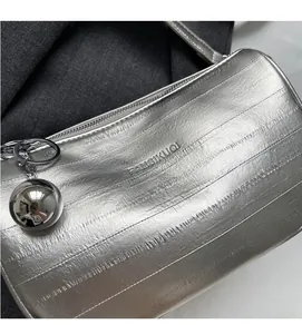 Dettaglio borsa Boston argento con trama goffrata e ciondolo a sfera in metallo lucido