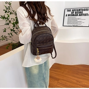 Mini brown leather backpack featuring cute bear prints and white plush charm on model
