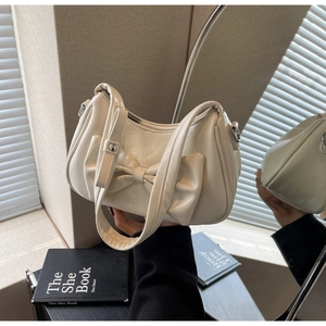 Detailed view of cream leather handbag featuring a large bow and silver zipper