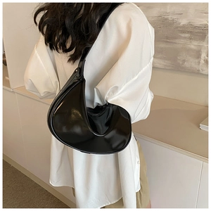 Detail einer glänzenden schwarzen Halbmond-Tasche aus Leder im minimalistischen Stil