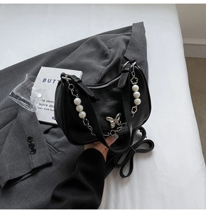 Detail of black matte hobo bag with silver butterfly and pearl flower chain
