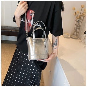 Detail of silver metallic bucket bag featuring vertical texture and adjustable strap