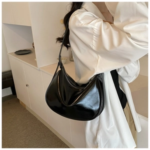 Detail der minimalistischen schwarzen Halbmond-Tasche aus glänzendem Leder