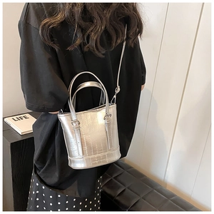 Detail of silver metallic bucket bag with dual handles and long detachable shoulder strap