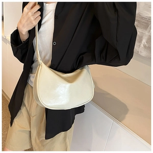 Detail einer cremefarbenen Halbmond-Tasche aus glattem Leder mit verstellbarem Riemen