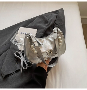 Detail of silver metallic bag featuring metal butterfly and pearl floral charms