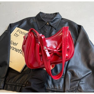 Detailed view of red glossy underarm bag with large decorative bow and metal zipper
