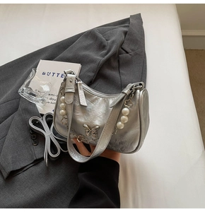 Detail of silver hobo bag with pearl flower chain and metal butterfly buckle on a blazer