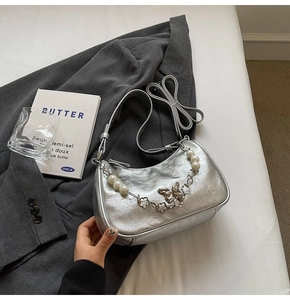 Silver crescent underarm bag with pearl butterfly chain detail on a suit jacket