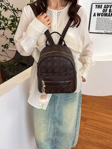 Brown faux leather backpack with bear print, gold zippers, and plush lamb charm accessory