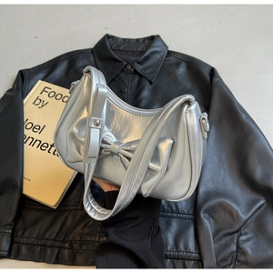 Detailed view of silver metallic handbag with oversized bow and half-moon silhouette