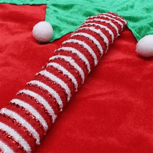 Detail of red and green velvet Christmas tree skirt with white pom-poms and candy cane motifs