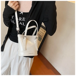 Close-up of white patent leather bucket bag with fashion text and adjustable strap