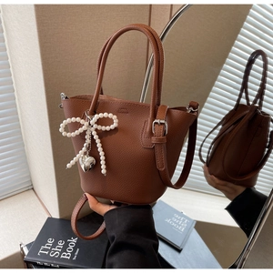 Close-up of brown litchi pattern bucket bag with pearl bow and silver heart pendant