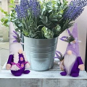 Close-up of spring lavender gnome figurines with plush hats and floral details