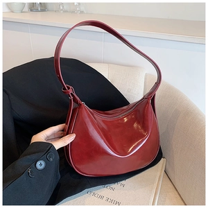Detail einer weinroten Lackleder-Schultertasche mit Reißverschluss und verstellbarem Gurt