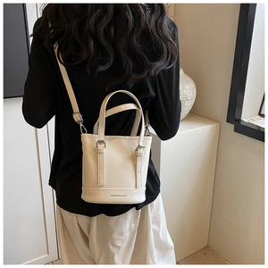 Rear view of model wearing a mini white bucket bag with fine leather texture