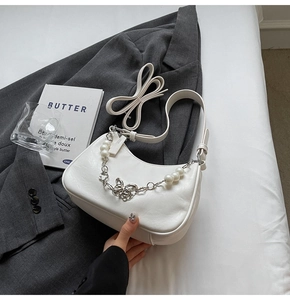 Detail of white crescent bag featuring large pearls and hollow butterfly metal chain