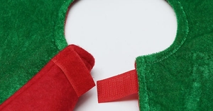 Detail of red velcro strap and green plush fabric stitching on the Christmas tree skirt