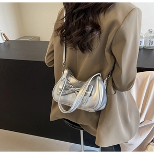 Detail of silver metallic handbag with large bow accent shown on model's shoulder