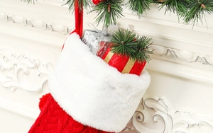 Dettaglio calza di Natale in maglia rossa con bordo in peluche bianco su un camino