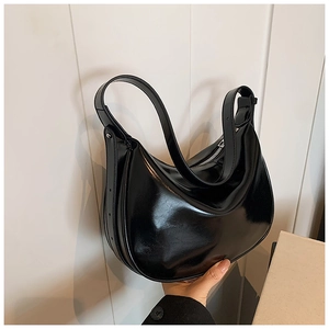 Detail einer schwarzen Hobo-Tasche aus glänzendem Lackleder mit Metallschnallen-Verstellung