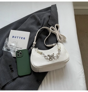 Detail shot of white semi-moon underarm bag with butterfly and pearl metal chain