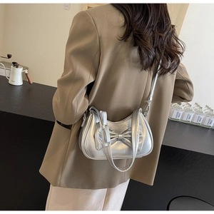 Detail of silver metallic shoulder bag with large bow decoration on brown blazer