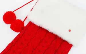 Dettaglio di calza natalizia in maglia rossa con bordo in finta pelliccia bianca e pompon