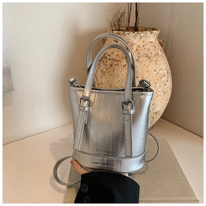 Detail of silver bucket bag with metallic texture, leather straps and logo print