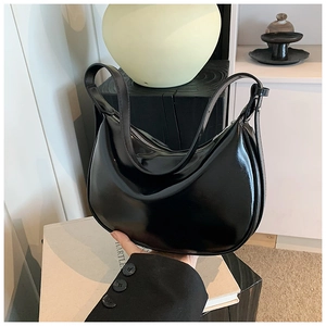 Detailansicht einer glänzenden schwarzen Halbmond-Schultertasche aus Lackleder mit Reißverschluss