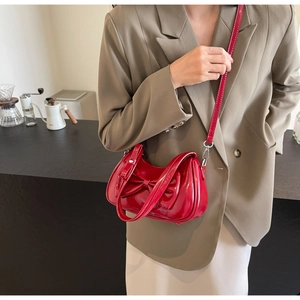 Detail of red patent leather shoulder bag with bow decoration on a khaki suit