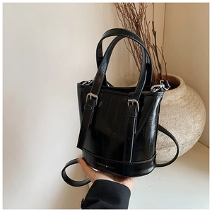 Detail of glossy black bucket bag featuring vertical ridges and adjustable straps
